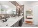 Bathroom vanity with double sinks, modern wallpaper, and a doorway to the bedroom at 9021 Winged Thistle Ct, Raleigh, NC 27617