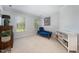 Bright bedroom featuring a blue settee, two windows, and a neutral color scheme at 9021 Winged Thistle Ct, Raleigh, NC 27617