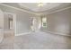 Open main bedroom with doorway to the bathroom, neutral colors, window, and tray ceiling at 915 Chapanoke Rd, Raleigh, NC 27603