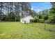 View of outbuilding in the backyard surrounded by a chain link fence and lush greenery at 100 Martindale Dr, Youngsville, NC 27596