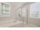 Bright bathroom featuring a shower with glass doors, a soaking tub, and natural light from two windows at 1006 Whistler St, Durham, NC 27713