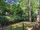 Private backyard featuring lush greenery, a classic black metal fence, and mature trees at 1105 Tazwell Pl, Raleigh, NC 27612