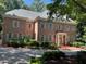 Charming two-story brick home with mature trees and manicured landscaping with a welcoming front entrance at 1105 Tazwell Pl, Raleigh, NC 27612