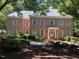 Charming two-story brick home with mature trees and manicured landscaping with a welcoming front entrance at 1105 Tazwell Pl, Raleigh, NC 27612