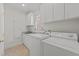 Bright laundry room featuring white cabinets, granite countertops, and modern washer and dryer units at 1105 Tazwell Pl, Raleigh, NC 27612