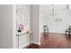 Hallway with hardwood floors, a decorative mirror on a table, and a chandelier-lit dining area in the background at 1109 Hemby Ridge Ln, Morrisville, NC 27560
