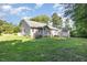 View of the backyard of the house with green grass and mature trees in a verdant, peaceful setting at 112 Avent Pines Ln, Holly Springs, NC 27540