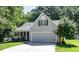 Charming home featuring a two-car garage and a cozy front porch, nestled among mature trees and lush greenery at 112 Avent Pines Ln, Holly Springs, NC 27540