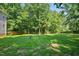 Lush backyard with green grass, mature trees, and a fire pit, perfect for outdoor enjoyment at 1205 Magnolia Hill Rd, Garner, NC 27529