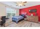 Cozy bedroom featuring a red accent wall, ceiling fan, and large window at 1205 Magnolia Hill Rd, Garner, NC 27529