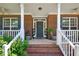 Inviting brick front porch with white railings, potted plants, and a stylish front door at 1205 Magnolia Hill Rd, Garner, NC 27529