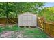 Backyard storage shed, with a wooden fence, and lush trees at 1205 Magnolia Hill Rd, Garner, NC 27529