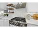 Elegant kitchen with stainless steel appliances, marble backsplash, and floating wood shelves at 129 Damsire Way, Cary, NC 27513