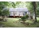 Back exterior showcasing the wooden deck with stairs, landscaped lawn, and wooded backdrop at 140 Baron Cir, Youngsville, NC 27596