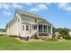 Well-maintained home featuring a screened-in porch, stone patio, manicured lawn, and lush landscaping at 142 Scarlet Oak Run, Clayton, NC 27520