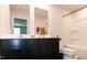 Modern bathroom featuring dual sinks, dark cabinetry, and tub/shower combo in the background at 1476 Burgundy Bluff Ln, Zebulon, NC 27597