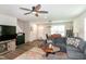 Open-concept living room with ceiling fan, comfortable seating, and hardwood floors seamlessly leading to the dining area at 1476 Burgundy Bluff Ln, Zebulon, NC 27597