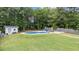 Landscaped backyard with an in-ground pool, shed, lounge chairs, and basketball hoop at 149 Great Oak Dr, Garner, NC 27529