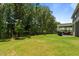 A well-manicured backyard with mature trees and a covered patio featuring a dining area and grill at 165 Hickory Grv Dr, Sanford, NC 27330