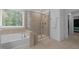Bathroom featuring a soaking tub, glass shower, and large window for natural light at 165 Hickory Grv Dr, Sanford, NC 27330