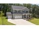 Stylish two-story home features a three-car garage, covered porch, and landscaped yard, perfect for curb appeal at 165 Hickory Grv Dr, Sanford, NC 27330