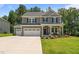 Beautiful two-story home with a three-car garage, inviting front porch, and meticulously landscaped front yard at 165 Hickory Grv Dr, Sanford, NC 27330