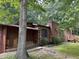 Side view of a charming brick home with a porch, woodpile and mature trees at 194 John Mitchell Rd, Youngsville, NC 27596
