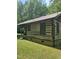 Rustic log cabin with a metal roof, surrounded by a lush green lawn and trees at 2011 Bowmantown Rd, Roxboro, NC 27574