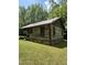Quaint log cabin with a metal roof, set in a green lawn, and surrounded by trees at 2011 Bowmantown Rd, Roxboro, NC 27574