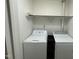 This laundry room includes both a modern washing machine and dryer set, and additional storage shelving at 205 Woodhaven Dr, Burlington, NC 27217