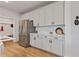 Kitchen featuring white cabinets, stainless steel appliances, wood-look floors, and adjacent mudroom with coat hooks at 21 Whistling Way # 17, Lillington, NC 27546