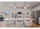 Open kitchen features white cabinets, an island with seating, modern pendant lighting, and seamless flow to a mudroom at 21 Whistling Way # 17, Lillington, NC 27546