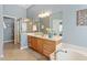 Bright bathroom with a glass shower, soaking tub, wooden cabinets, large mirror, and ceramic tile flooring at 2941 Grandview Heights Lane Ln, Raleigh, NC 27614