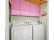Bright laundry room featuring white appliances and pink cabinets for storage, adding a fun pop of color at 302 Bradley St, Burlington, NC 27215