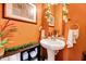 Stylish powder room featuring an above-counter sink, decorative accents, and vibrant orange walls at 3217 Enchanting Way, Raleigh, NC 27616