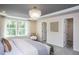 Serene bedroom with a plush bed, a modern chandelier, large windows, and a cozy armchair, offering a relaxing retreat at 331 Bridle Brook Way, Fuquay Varina, NC 27526