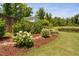 Well-manicured backyard with flowers, mulch, grass and a pond in the back at 408 Brierley Dr, Apex, NC 27523