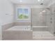 Spa-like bathroom featuring soaking tub and glass shower with tile accents, creating a relaxing retreat at 408 Brierley Dr, Apex, NC 27523