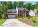 View of a brick home featuring a two-car garage and driveway with mature landscaping at 4309 Omni Pl, Raleigh, NC 27613
