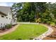 Beautifully manicured backyard featuring a stone path, lush green lawn, and brick retaining wall at 4412 Pamlico Dr, Raleigh, NC 27609