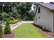 Side yard with landscaped garden and brick retaining wall, and a lush lawn at 4412 Pamlico Dr, Raleigh, NC 27609