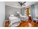 Bedroom with two beds, wood floors, ceiling fan, and natural light from the French doors at 4412 Pamlico Dr, Raleigh, NC 27609