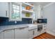 Bright kitchen featuring white cabinets, farmhouse sink, blue tile backsplash, and wood floors at 4412 Pamlico Dr, Raleigh, NC 27609