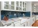 Kitchen with white cabinets, marble counters, farmhouse sink, and blue subway tile backsplash at 4412 Pamlico Dr, Raleigh, NC 27609