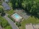 Aerial view of a community pool, lounge chairs, a tennis court, and surrounded by trees at 4600 Townesbury Ln, Raleigh, NC 27612