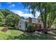 Well-maintained backyard featuring a deck, green grass, mature trees, and a retaining wall at 4600 Townesbury Ln, Raleigh, NC 27612
