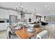 Open dining area with a modern chandelier, a dining table set for a meal, and a view of the kitchen at 5032 Jowetts Walk Dr # 26, Cary, NC 27519