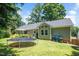 Home exterior showcasing a large grassy yard, wood deck, trampoline, and exterior paint color at 5320 Middleton Rd, Durham, NC 27713