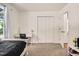 This bedroom includes neutral carpet and paint, closet with white bifold doors, desk, and bright window at 5320 Middleton Rd, Durham, NC 27713