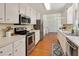 Kitchen with stainless steel appliances, white cabinets, and hardwood floors that open to the dining area at 5320 Middleton Rd, Durham, NC 27713